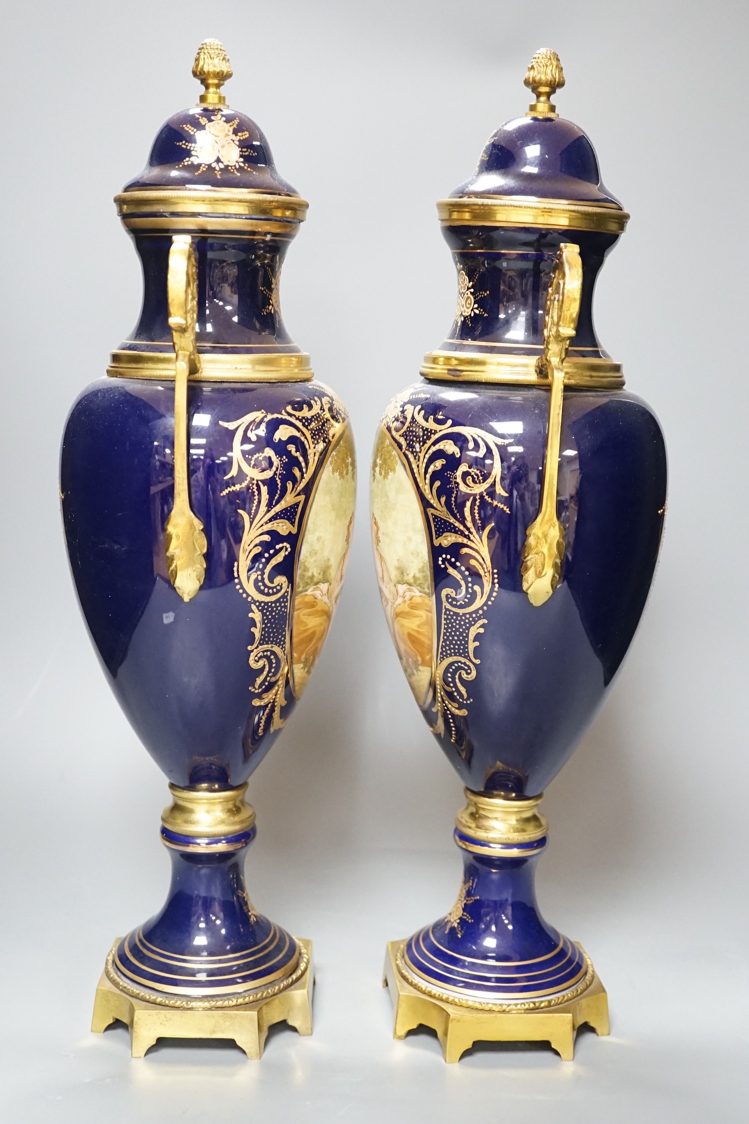 A pair of Sevres style urns and covers, with gilt metal mounts, 50 cms high